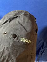 Side view of black bucket hat showing Aigle brand patch and snap button details.