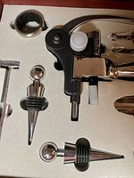 Close-up of corkscrew, bottle stoppers, and other items in foam insert.
