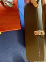 Black closed box with silver clasp being held to show size and condition