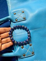 Close-up of lapis lazuli beaded bracelet resting on the purse.