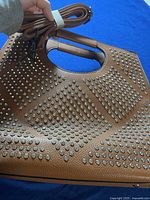 Angle top side view of brown rhinestone heavily embellished purse showing the built-in handle and attached shoulder strap.