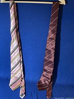 Two men's ties hanging, showing full length and striped pattern of each.
