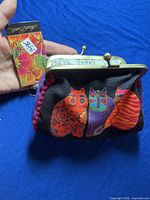 Photo of a new fabric purse with colorful cat pattern and metal clasp, showing the front detail and attached tag.