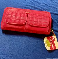 Photo of closed pink Lug Double Backflip wallet showing quilted fabric front and brand tag with price tag attached