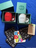 Two Starbucks espresso cups, red and white, each in a green box with the Starbucks Siren logo, shown alongside four Happy Birthday greeting cards including one multicolored card and three black cards with large birthday text.