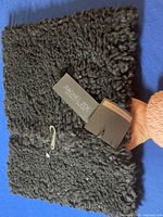 Close-up image of the black faux fur neck warmer showing texture and attached Rachel Zoe brand tag.