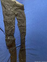 Black sheer tights with sequin sparkle laid out on blue fabric background