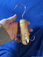 Wooden tie and scarf hanger shown in hand with metal hanging hook and side hooks visible.