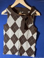Front view of brown and gray argyle sleeveless knit top with fabric tie detail on hanger.