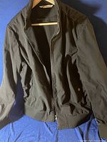 Full view of the black men's windbreaker jacket laid flat showing front and design details