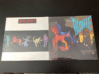 Front covers of both sealed vinyl LPs by Heart and David Bowie shown side by side on black surface.