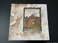 Front cover of Led Zeppelin IV LP record sleeve with iconic painting of man carrying sticks and wallpaper background showing some wear and peeling.