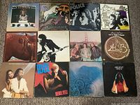 Photo showing all 12 LP records arranged in 3 rows of 4 on carpet.