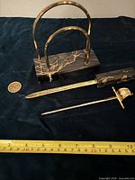 Photo showing the three main items: brass and marble mail holder, marble and brass letter opener, and brass sword mail opener with measuring tape and coin for scale.