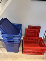 Four large blue Rubbermaid storage bins stacked with lids placed on top.