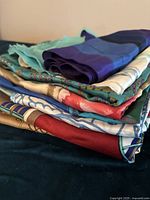 Stacked view showing folded silk scarves with visible vibrant colors and varied patterns.