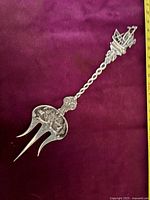 Full view of the Dutch sterling silver meat fork on a burgundy fabric background showing handle and fork tines.