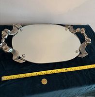 Full view of the oval mirrored vanity tray measuring about 15 inches in length with decorative silver-tone edges and handles.