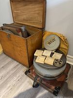 Wooden chest open showing metal film canisters and cardboard film boxes