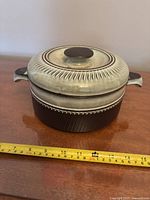 Photo of closed vintage Denby Rondo stoneware crock with lid on wood surface and measuring tape showing approx. 18 cm width