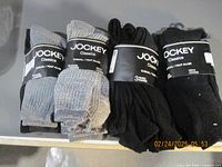 Four sets of men's Jockey Classics socks each containing 3 pairs, laid out showing packaging and colors (black, gray).