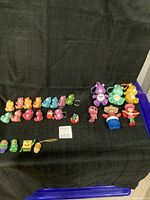 Several collectible bears and character keychains displayed on black fabric, various colors and sizes shown.