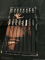 Front view of boxed DVD set showing spines of 7 Nightmare On Elm Street titles with claw design and box art inside.