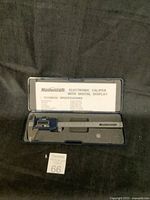 Mastercraft electronic caliper in blue and steel, in open case with foam padding and instruction sheet visible.