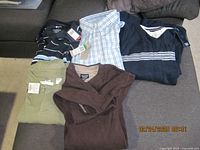 Lot of 5 men's large size clothing items, all new with tags, displayed on a couch including sweaters and shirts