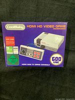 Photo of the CoolBaby HDMI HD video game boxed console showing the front of the packaging with console and controller image, and game count.