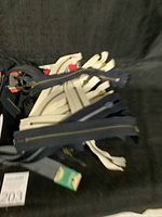 Lot of various sewing zippers in multiple colors and sizes laid out on black background.