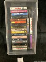 Top view of box containing stacked vintage music cassette tapes with visible labels from various artists and genres.
