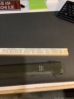 Vintage K&E slide rule laid on black surface with green protective case beside it showing the K&E brand and model number.