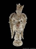 Full view of the distressed cherub angel statuette with detailed crown, wings, and rounded floral base against black background