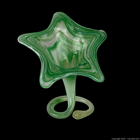 Full view photo showing the green and white hand blown glass vase shaped like a star with swirling patterns and a curled stem base.