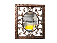 Front view of large rectangular mirror with oval reflective surface and ornate metal frame with leaf and scroll designs.