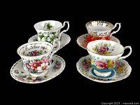 Four Royal Albert fine bone china cups and saucers with floral and gold designs on a black background