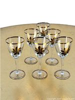 Set of six vintage Mid-Century Modern wine glasses with gold floral accents and gold rim on the table.