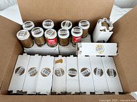 Multiple boxes of Sheffield metallic leaf finish gold paint jars, some opened, in original packaging inside a cardboard box.