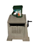 Front angled view of beige Suncast hose reel with hand crank and Scotts Turf Builder green seed spreader attached on top