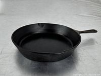 Side angle view of the cast iron frying pan, showing the cooking surface and one pouring spout.