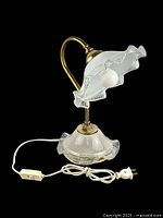 Full view of vintage brass gooseneck table lamp with ruffled glass shade, white cord, inline switch, and two-prong plug on black background.