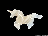 Side view of the alabaster unicorn figurine showing the detailed horn, mane, and rearing posture.