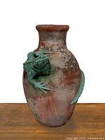 Front view of the vintage clay planter showing the large green lizard sculpture on the front side.