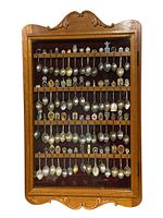 Front view of vintage oak hanging spoon display case filled with collectible spoons arranged on five wooden racks inside a burgundy fabric background.