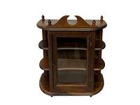 Front view of vintage wooden wall display case showing glass door and top decorative finials.