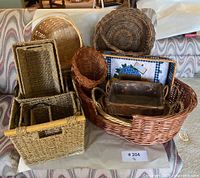 Front view of stacked baskets on floor including oval wicker basket, bamboo basket, and nested woven baskets
