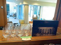 Photo showing one set of 8 Mikasa stemless wine glasses out of the box, with original box displaying the set.