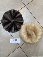 Two berets on floor, one dark brown and one cream colored, shown from top down view