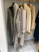 Four women's coats hanging: leopard-print faux fur, taupe llama fur by Del Mod, cream shearling-style, tan teddy-style.